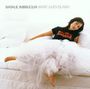 "NATALIE IMBRUGLIA WHITE LILIES ISLAND." Frau in weißem Kleid liegend, entspannt auf einem weißen Sofa.