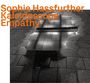 „Sophie Hassfurther Kaleidoscope Empathy“ in orange, über einem reflektierenden Pflastersteinboden mit Wasserlachen.