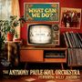 "What Can We Do?" auf buntem Schild. Darunter retro Fernseher mit "Please Stand By". Wohnzimmer mit Pflanzen und Schallplatten.