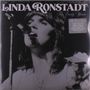 "Linda Ronstadt The Early Years." Schwarz-weiße Darstellung einer Frau beim Singen und Gitarrespielen mit Mikrofon.
