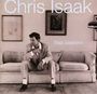 Text: "Chris Isaak," "Baja Sessions." Ein Mann in Anzug sitzt nachdenklich auf einem Sofa, gerahmte Bilder im Hintergrund.