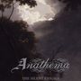 Text: „Anathema – The Silent Enigma“. Dunkle, wolkenverhangene Landschaft mit Bäumen, dramatische Wolkenformation.
