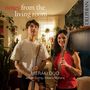 „notes from the living room“, „MERAKI DUO“, „James Girling | Meera Maharaj“. Zwei Personen mit Gitarre und Flöte im Wohnzimmer.