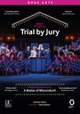 "Trial by Jury", eine lebhafte Szene mit Richtern und Tänzerinnen in leuchtenden Kostümen auf einer Bühne.