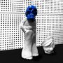 Eine abstrakte Skulptur mit einem blauen Totenkopf auf einem weißen Körper, neben einer ähnlichen Form auf schwarzem Boden.