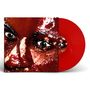 Nahaufnahme eines Gesichts mit glitzernder Haut, rotes Vinyl sichtbar daneben.