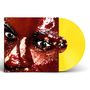 Ein leuchtend gelbes Vinyl mit einem Nahaufnahme-Gesicht, glitzernde Effekte und intensive Augen.