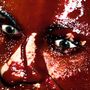 Ein Gesicht mit intensivem, glitzerndem roten Licht- und Schattenspiel, das die Augen stark hervorhebt.