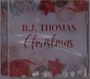 Text "B.J. THOMAS Christmas" in roten Buchstaben, umgeben von roten Sternen, Tannenzapfen und Zweigen.