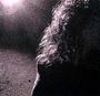 Kein Text vorhanden. Ein grobkörniges, schwarz-weißes Bild zeigt Lichtstrahlen und teilweise beleuchtete lockige Haare.