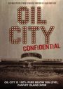 OIL CITY CONFIDENTIAL. Gebäude mit Rundbau und Menschen im Vordergrund, zerklüfteter Boden.