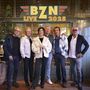 Text: "BZN LIVE 2025". Sechs Personen stehen nebeneinander vor einer dekorativen Wand.