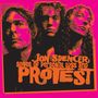 "Jon Spencer: Songs of Personal Loss and Protest" in oranger Schrift vor einem pinken Hintergrund. Drei Porträts.