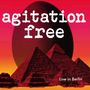 Text: "agitation free", "Live in Berlin". Illustration: Pyramiden vor einem großen, dunklen Ei, Hintergrund in Rot-Orange.