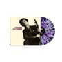 „WOODY GUTHRIE“ steht in lila Schrift. Eine retro Aufnahme zeigt einen Mann mit einer Gitarre in dunkler Kleidung. Eine Schallplatte hat einen violett-weißen Splatter-Effekt.