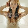 „Innocent Eyes“ und „Delta Goodrem“ in eleganter Schrift. Frau mit langen Haaren, trägt ein ärmelloses weißes Kleid.