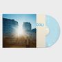 Text: "COLI"

Eine sonnige Stadtszene mit einem Menschen vor Gebäuden und einer blauen Vinyl-Schallplatte.