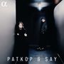 Text: "PATKOP & SAY". Zwei Personen stehen in einem dunklen Flur. Eine Person lehnt an der Wand, die andere steht im Hintergrund.