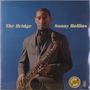 „The Bridge“ und „Sonny Rollins“ steht auf blauem Hintergrund. Ein Mann hält ein Saxophon.