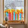 Eine Reihe bunter Kerzen aus Transparentpapier schmückt ein Fenster, dahinter schneebedeckte Bäume.