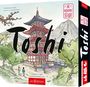 Text: "Toshi", "Geplant in der Spielewerkstatt von arsEdition", "Die Blühende Stadt". Illustration eines Pagodentempels vor Berg.