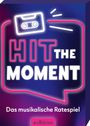 „HIT THE MOMENT“ in Neonoptik, Kassette, Text: „Das musikalische Ratespiel“, „arsEdition“. Farben: Pink, Blau.