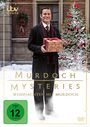 "Murdoch Mysteries: Weihnachten mit Murdoch." Ein Mann im Anzug hält ein Geschenk, vor einem weihnachtlichen Hintergrund.