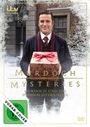„MURDOCH MYSTERIES: MURDOCH UND DAS WEIHNACHTSWUNDER“, Mann in Anzug mit rotem Schal hält Geschenk, winterliche Szene.