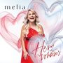 Der Text "melia" steht oben links, "Herz voraus" unten rechts. Eine blonde Frau in rotem Kleid lächelt vor bunten Herzen.