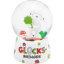 Text: "GLÜCKS-BRINGER". Eine Schneekugel mit Schaf, Kleeblatt und Fliegenpilzen auf einer weißen Basis.