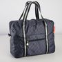 Rotes Etikett mit "LOQI". Dunkelblaue Tasche mit schwarz-weißen Streifen und geometrischem Muster.