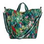Aufschrift "COCON". Eine bunte Tasche mit Papageien und Tropenmuster, zwei grünen Tragegriffen und einem gestreiften Schultergurt.