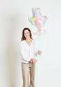 Eine lächelnde Person hält einen pastellfarbenen, sternförmigen Ballon mit floralen Mustern.