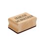 Ein Holzstempel mit der Aufschrift "Fröhliche Weihnachten." Rechteckige Form mit rotem Stempelkissen unten.