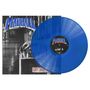 „MADBALL“ und „Side A“ sind in großen Buchstaben zu sehen. Eine blaue Vinyl-Schallplatte liegt teils auf einem Cover.