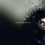 Text: "Gary Numan. Dead Son Rising."  
Rechts sieht man das Gesicht eines Mannes mit dunklen Haaren in einem düsteren Umfeld.