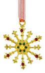 Ein goldenes Schneeflockenornament mit roten Steinen, einer grünen Blütenmitte und einem roten, gemusterten Band.