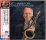 "SCOTT HAMILTON LIVE AT ELBJAZZ FESTIVAL 2024" steht in englischem Text. Ein älterer Mann hält ein Saxophon.