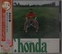„What's going on T-honda and his orchestra“. Japanischer Text auf rotem Streifen links, Mann sitzt auf Stuhl im Gras.