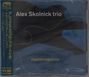 Text: "Alex Skolnick trio", "TRANSFORMATION". Eine abstrakte Illustration in Blau und Schwarz mit einem goldenen Logo links oben.