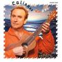 "Colin Hay Man@Work [acoustic vinyl]". Ein Mann in orange hält eine Ukulele vor einem Wellengemälde.