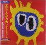 Text: "screamadelica primal scream". Illustration: Gelber, sonnenähnlicher Umriss auf rotem Hintergrund mit blauer Mitte und schwarzen Augen.