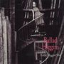 „Ballad Higgins“ und „Eddie Higgins Trio“. Eine Frau steht auf einer Wendeltreppe in einem Gebäude voller Holzbalken.