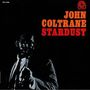 Text: "JOHN COLTRANE STARDUST". Ein Musiker in einem Anzug hält ein Saxophon, umgeben von einem dunklen Hintergrund.