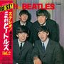 Japanischer Text links, oben „THE BEATLES“. Vier Männer in Anzügen lächelnd in die Kamera schauend.