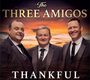 "The Three Amigos" und "Thankful". Drei Männer in Anzügen vor einem Sonnenuntergangshimmel.