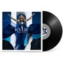„KYLIE APHRODITE“ steht auf einem Albumcover mit einer Person, die ein blaues Kleid trägt, die Arme ausgebreitet. Eine Schallplatte ist daneben.
