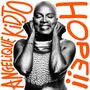 ANGELIQUE KIDJO, HOPE!! Eine Frau lächelt mit geschlossenen Augen und hält sich die Hände an die Ohren.