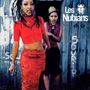 Text: "Les Nubians." Zwei Frauen stehen vor einer Holzwand, die vordere trägt ein rotes Outfit mit einem langen Rock.