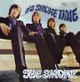 „…It's Smoke Time“ in blauer, geschwungener Schrift oben. „The Smoke“ in Weiß unten. Vier Männer in Anzügen sitzen auf einer Bank.